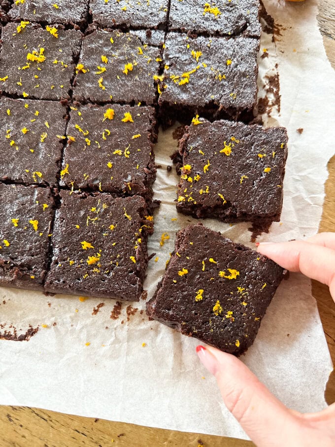 A slab of Chocolate Orange Black Bean Brownies cut into individual squares and decorated with grated Orange peel.  